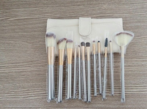 A set of various makeup brushes, including a Sweet Deals Persian makeup brush, neatly arranged to the left of a white brush holder, all positioned on a wooden surface.