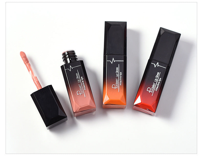 Three long-lasting Sweet Deals lip glosses in different shades with one applicator removed and lying beside the central peach-colored tube, against a white background.